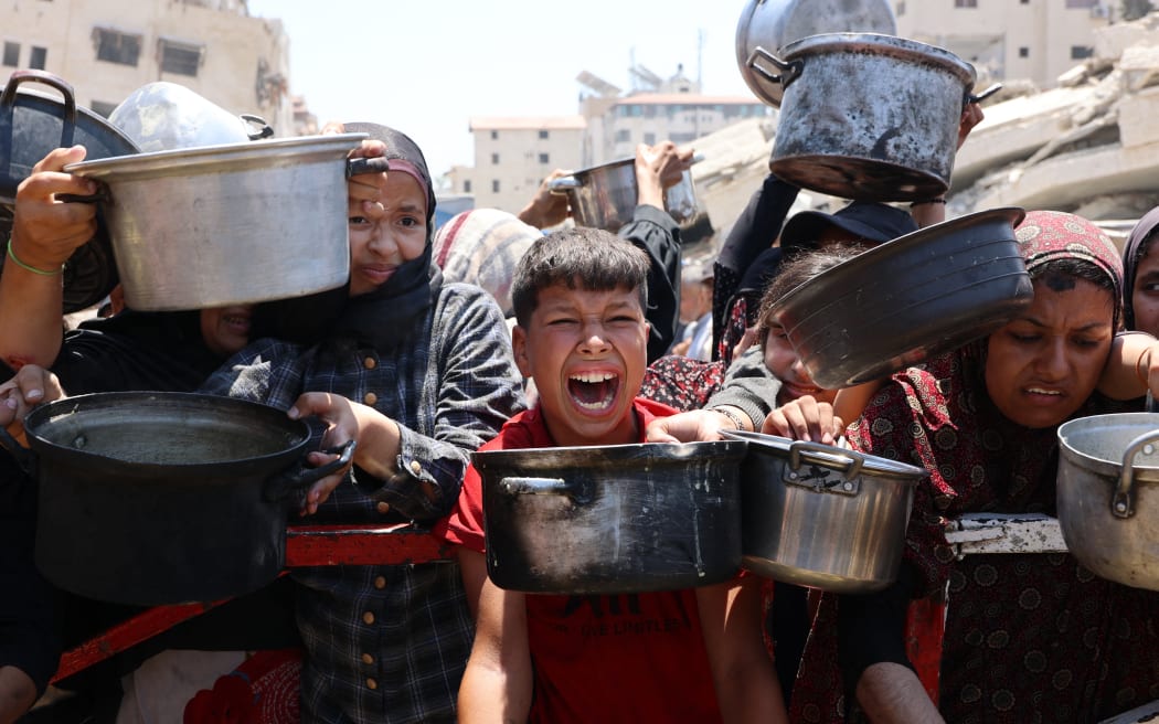 Palestinians crowd at a lentil soup distribution point in Gaza City in the northern Gaza Strip on July 27, 2025. (Photo by Omar AL-QATTAA / AFP)