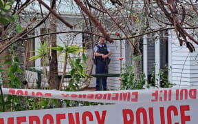 An armed police officer stands guard outside a house in Te Atatū Peninsula on 11 September, 2023.
