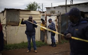 South African Police Service (SAPS) officers put up crime scene tape at the scene of an attack at a tavern in Bekkersdal on December 21, 2025. Nine people were killed when gunmen opened fire at a bar outside Johannesburg early on December 21, 2025.
Ten more were wounded in the early morning attack at the tavern at Bekkersdal, in a gold mining area around 40 kilometres (25 miles) southwest of the city. (Photo by EMMANUEL CROSET / AFP)