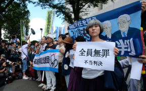 Activists hold placards in reaction during a rally in front of the Tokyo District Court in Tokyo after the court acquitted three former officials from the firm that operated the Fukushima nuclear plant.