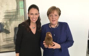 Jacinda Ardern and Angela Merkel with a kiwi soft toy.