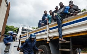 Zimbabwean anti-riot police forces watch men, arrested during violent protests triggered by a sudden rise in fuel prices announced by Zimbabwean President, for their hearing in Harare,