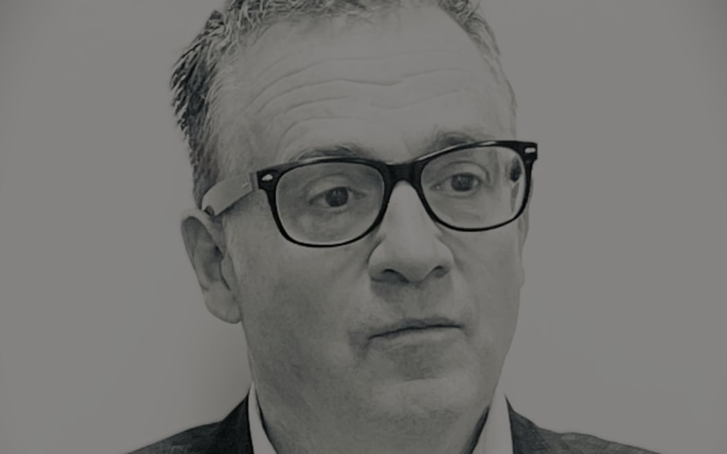 This is a head and shoulders shot of Detective Superintendent Darryl Sweeny. He is looking slightly off centre and gazing into the distance. Darryl is wearing glasses and a patterned suit jacket.