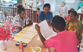 Mama Bank officer registering women in the Markham Bridge Community, 2022 (Eddison Silas)