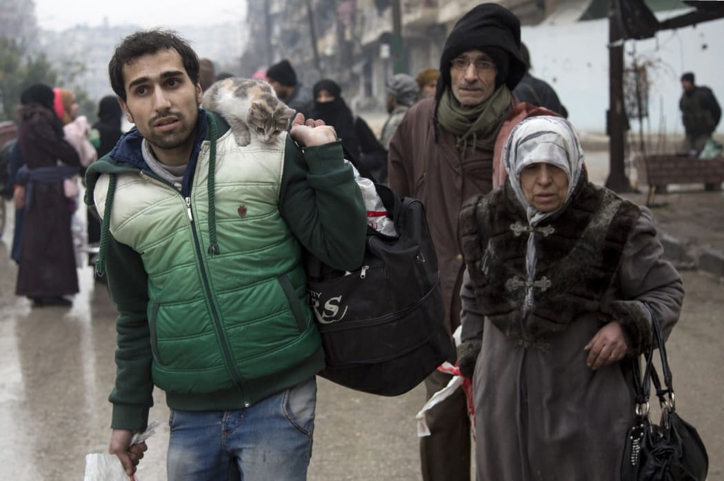 Syrians leave a rebel-held area of Aleppo towards the government-held side on 13 December, 2016.