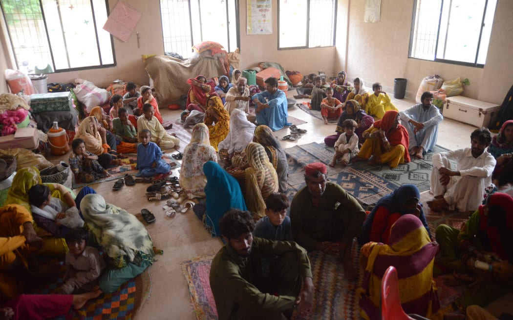 Displaced people wait to get food and other assistance after fleeing their flood-hit homes, from different districts of Karachi, Pakistan, on August 27, 2022. Flash floods caused by abnormally heavy monsoon rains have killed hundreds of people across Pakistan over the last two months, officials said Monday, as rescuers backed by troops raced against time to evacuate thousands of marooned people.