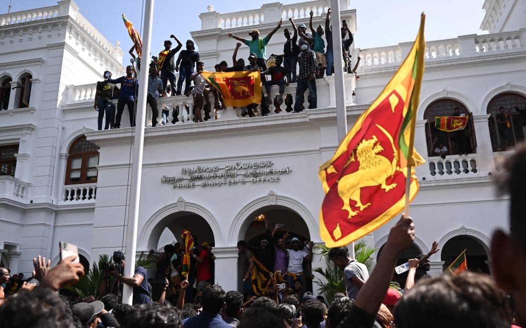 Demonstrators wave Sri Lankan flags during an anti-government protest in the office building of Sri Lanka's prime minister in Colombo on 13 July 2022.