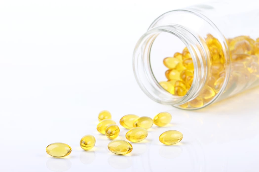 Macro view of vitamin D capsules on white with bottle in background