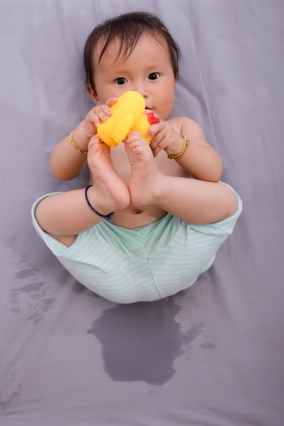 A photo of a baby lying in a wet patch after  bedwetting