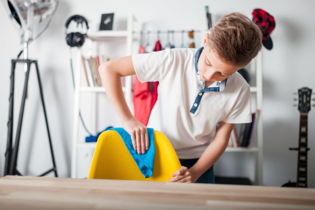A photo of a Preteen boy doing housework and cleaning his room