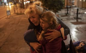 An Ukrainian refugee from from the Black Sea port city of Odessa, hugs two children as they arrive in Athens by bus, following the Russian invasion of Ukraine on March 6, 2022.