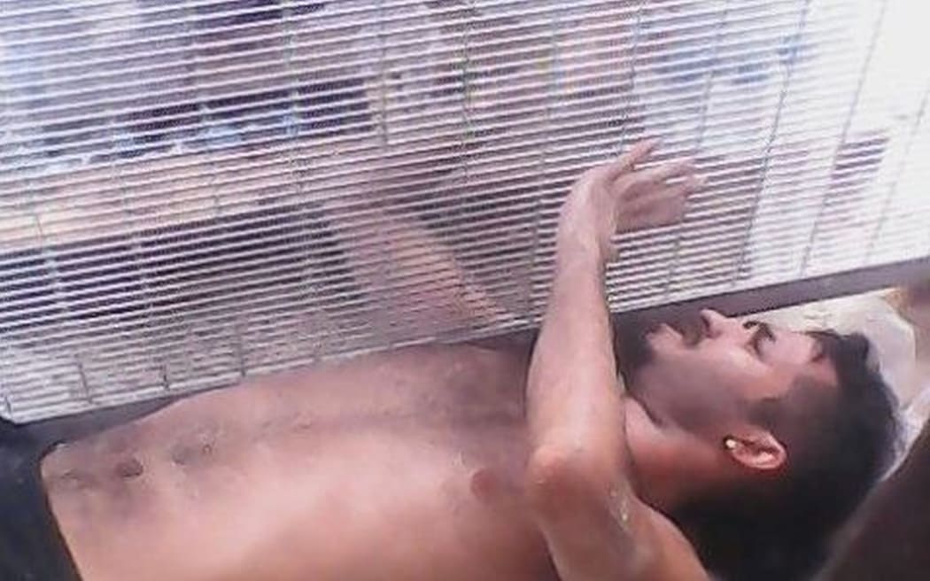 An asylum seeker tries to reach for drinking water outside of the Manus Island compound.