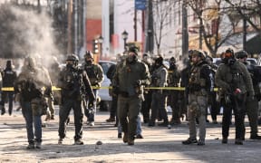 Federal agents stand near police tape as demonstators gather near the site of where state and local authorities say a man was shot by federal agents earlier in the morning in Minneapolis, Minnesota, on January 24, 2026. Minnesota Governor Tim Walz said Saturday that federal agents deployed in Minneapolis as part of a sweeping immigration crackdown had carried out "another horrific shooting," less than three weeks after the fatal shooting of Renee Good. (Photo by ROBERTO SCHMIDT / AFP)