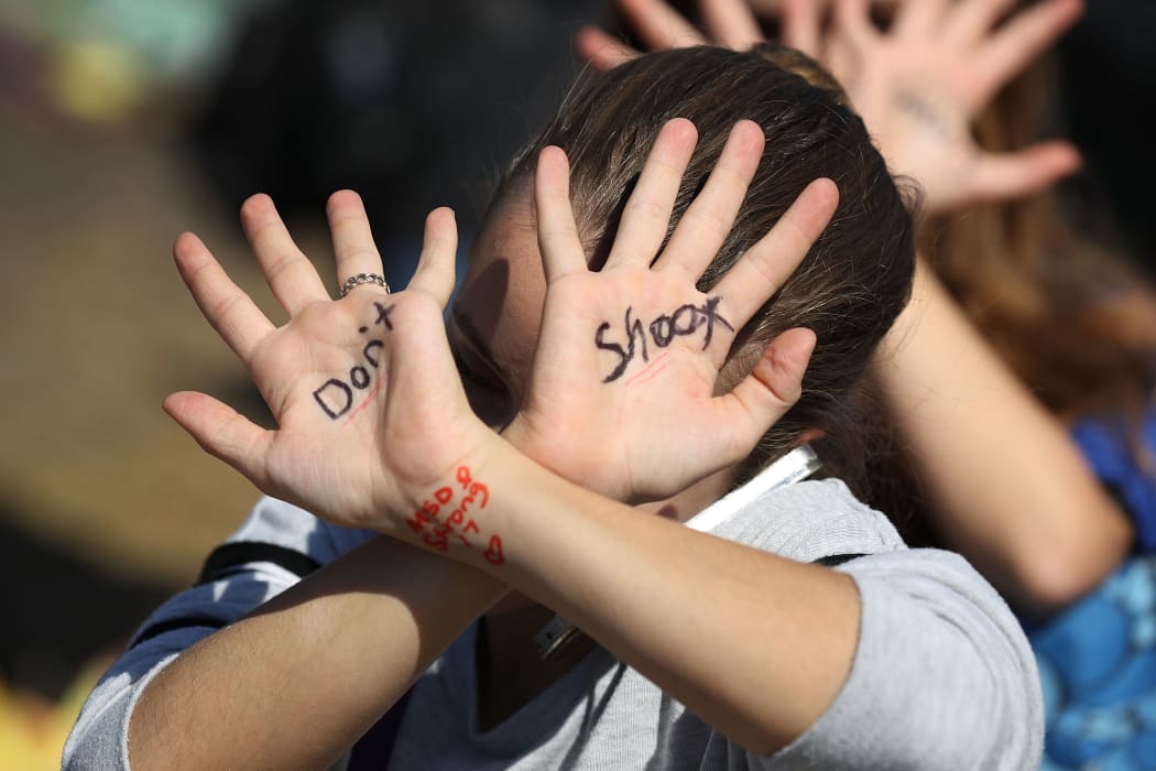 A student from has the words,'don't shoot,' written on her hands as she joins with other students at Marjory Stoneman Douglas High School after walking out of their school.