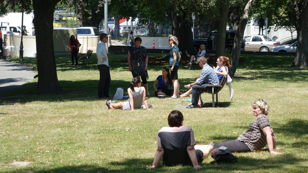 Office workers in the shade next to the Avon River in Christchurch.
