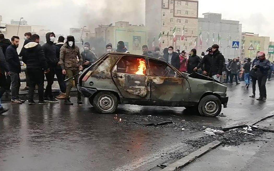 Iranian protesters gather around a burning car during a demonstration against an increase in gasoline prices in the capital Tehran, on November 16, 2019. -