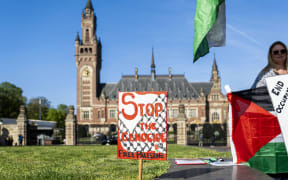 A demonstrator stands beside a placard outside the International Court of Justice as an interrogation on Israel's humanitarian obligations towards Palestinians takes place at the International Court of Justice, in The Hague on April 28, 2025. The UN's top court opened on April 28, 2025, a week of hearings on Israel's humanitarian obligations towards Palestinians, more than 50 days into its total blockade on aid entering war-ravaged Gaza. United Nations representatives will start the five days of sittings at the International Court of Justice in The Hague, followed by a Palestinian submission. (Photo by Lina Selg / ANP / AFP)