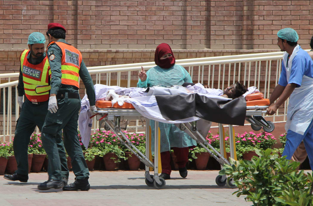 Pakistani rescue workers and paramedics with a burns victim injured after the oil tanker fire.
