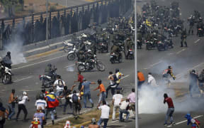 Opponents to Venezuela's President Nicolas Maduro confront loyalist Bolivarian National Guard troops firing tear gas at them, outside La Carlota military airbase in Caracas, Venezuela, Tuesday, April 30, 2019.
