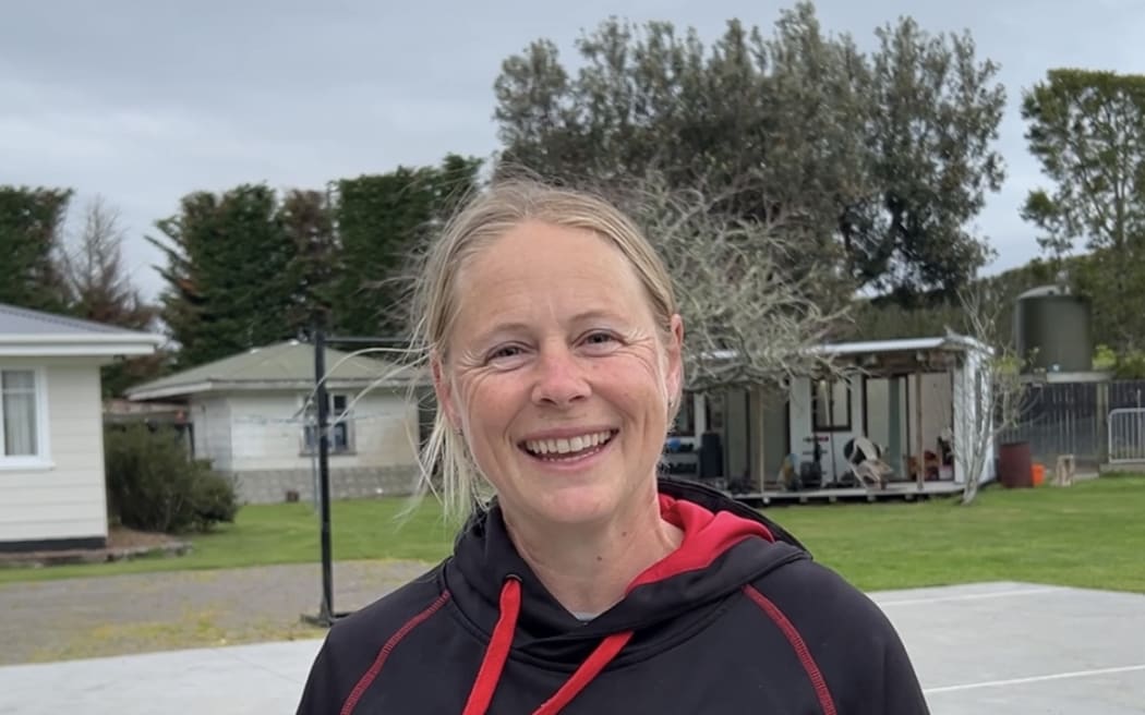 Portrait of a woman standing in front of a basketball court.