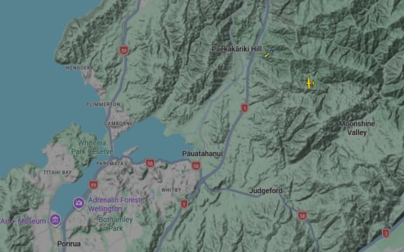 A rescue helicopter can be seen searching the area after a helicopter crash in Paekākāriki Hill.