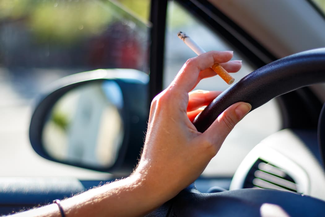 Smoking a cigarette in a car.
