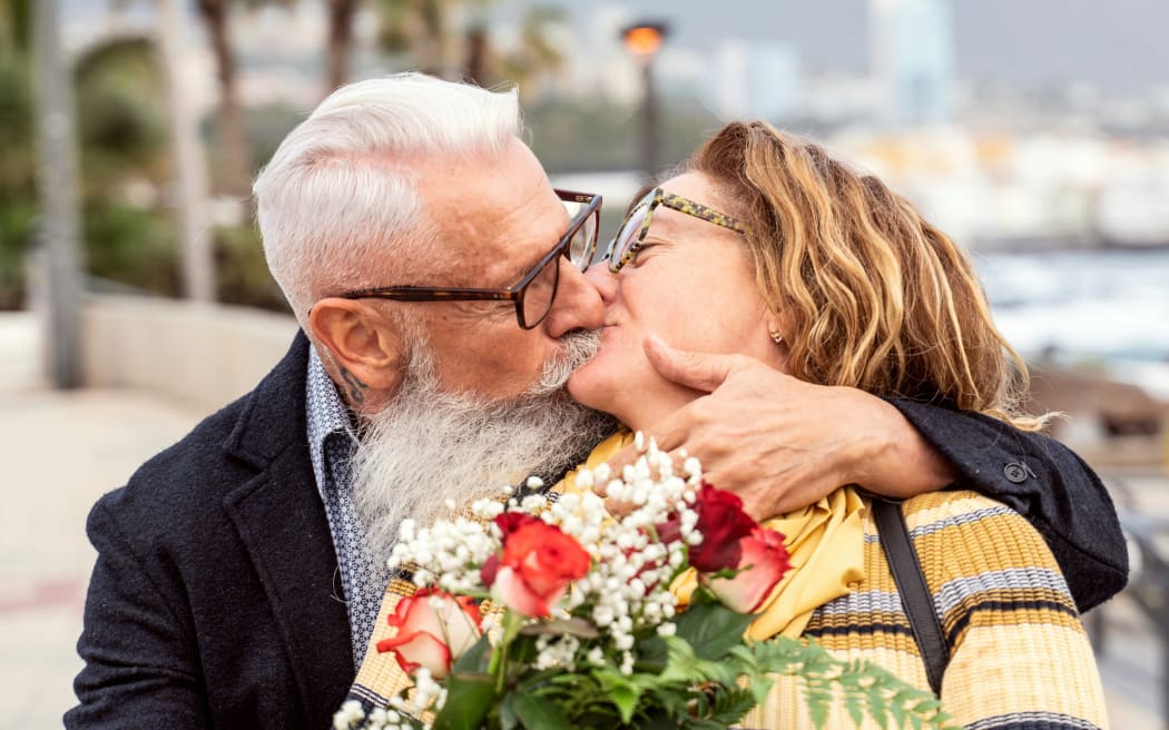 Older couple embracing while holding flowers
