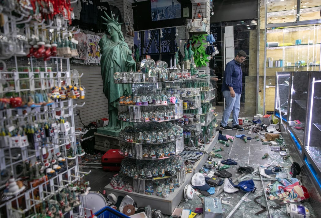 A shop owner looks over damage in a looted souvenir shop near Times Square a