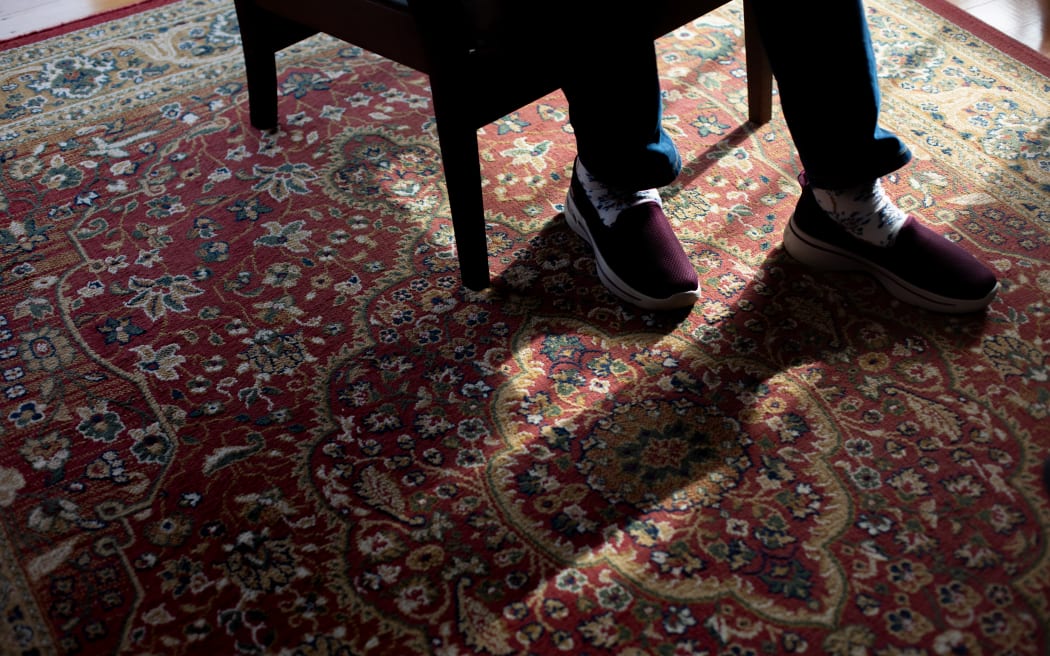 Kerry Hodgson sits in her lounge as she recalls how the ECT treatments she had has effected her life. Long shadows fall across the carpet as sun shines in through a large window.