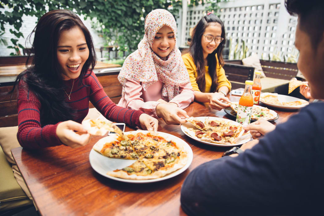 A photo of an ethnically diverse group Of Young Friends Enjoying a Meal In Outdoor Restaurant