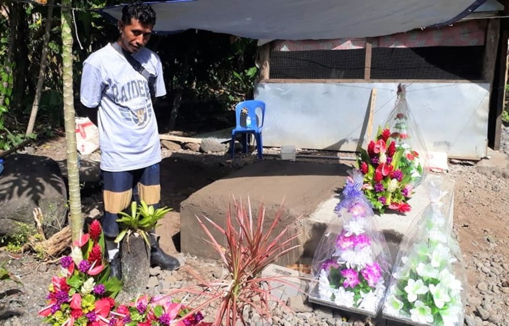 The father Tu'ivale Luamanuvae of Lauli'i Village beside the grave of his three children who died of measles