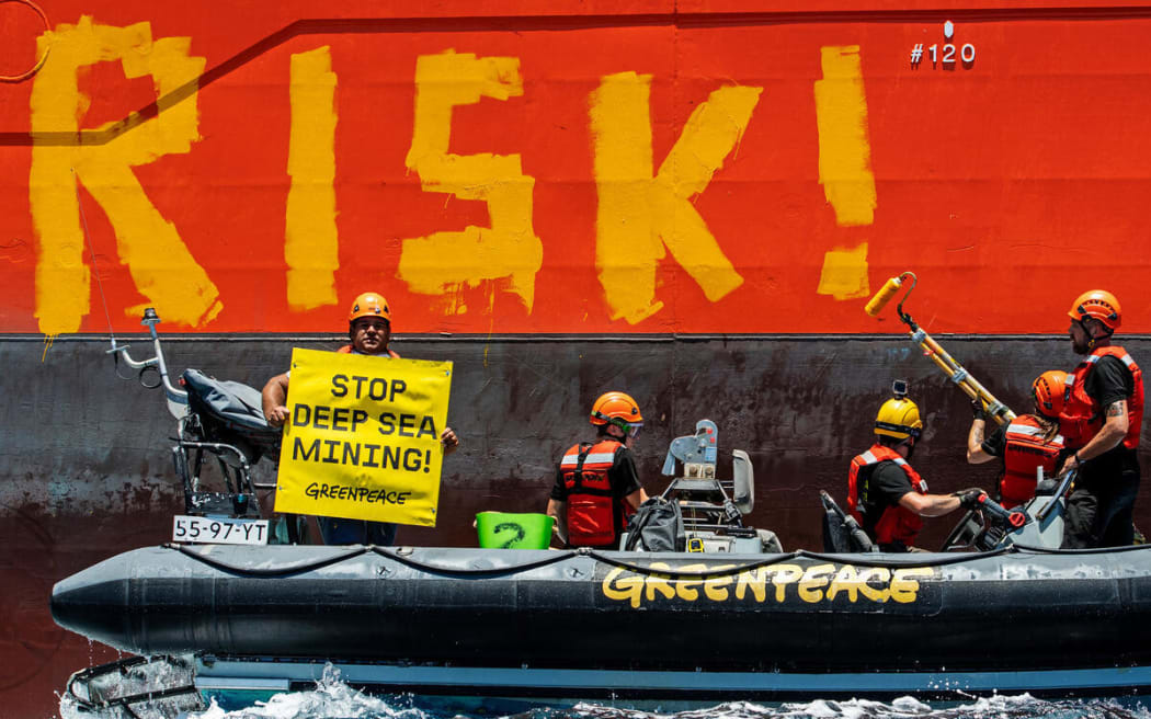 Greenpeace International activists paint the word 'RISK!' on the starboard side of Normand Energy, a vessel chartered by the Belgian company Global Sea Mineral Resources (GSR).