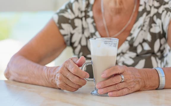 Cropped photo of stylish senior woman holding cup of coffee outdoors