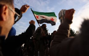 Syrian rebel fighters celebrate at the Clock Tower in the heart of the central city of Homs early on December 8, 2024, after rebel forces entered Syria's third city overnight. - Hayat Tahrir al-Sham (HTS) and allied anti-goovernment factions have pressed a lightning offensive since November 27, sweeping swathes of the country from government control, including major cities Aleppo, Hama and Homs. (Photo by Aaref WATAD / AFP)