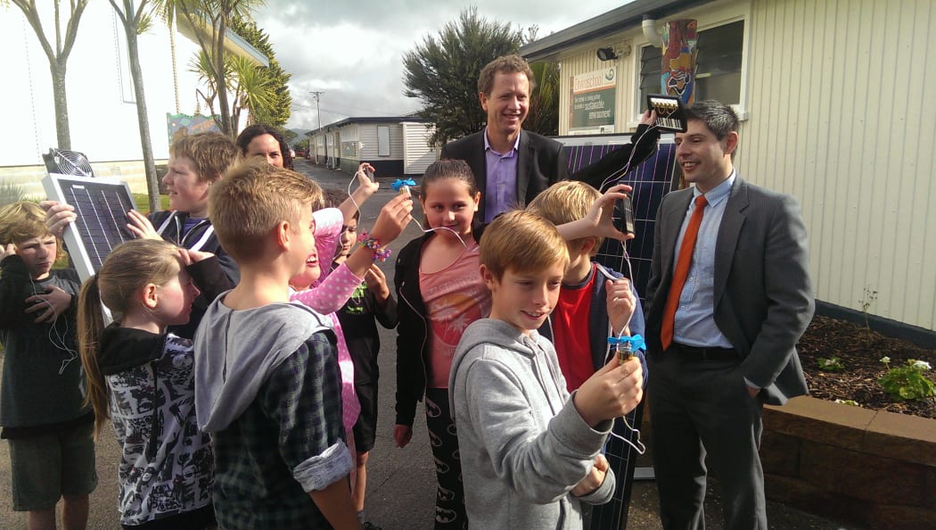 Russel Norman and Gareth Hughes and Laingholm Primary School students looking at solar equipment.