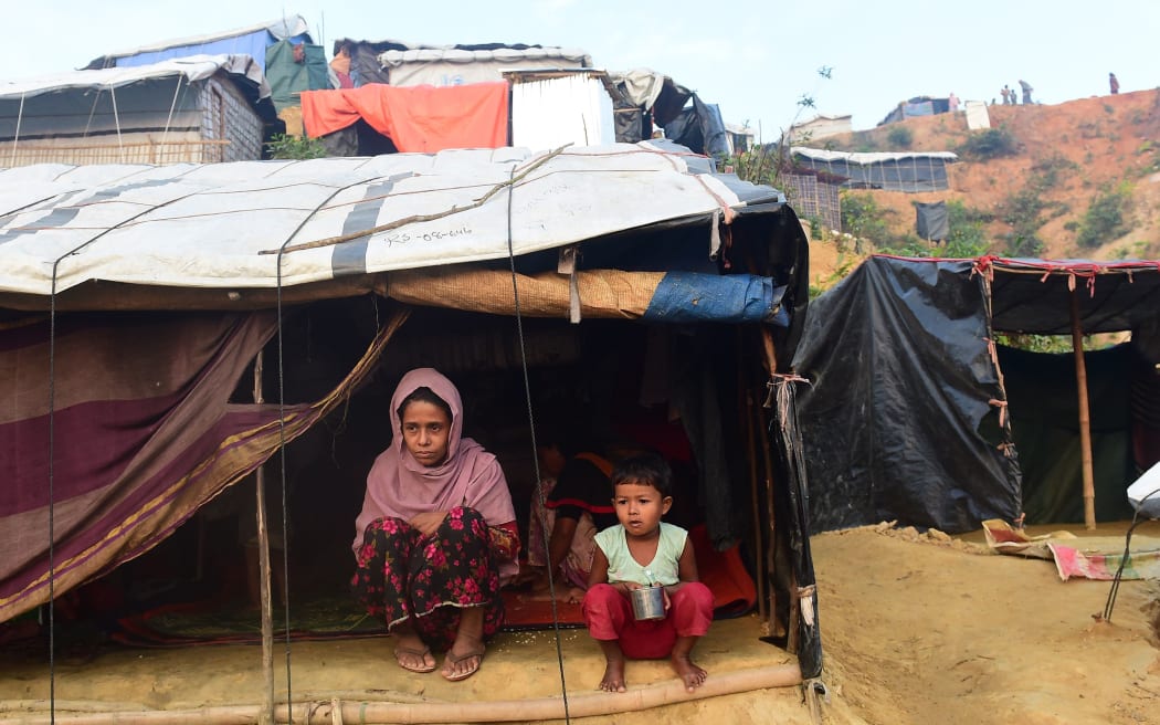 Rohingya refugees sit in front of their makeshift shelter