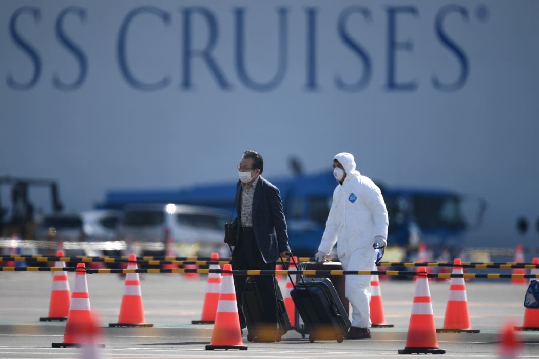 A passenger, left, disembarks from the Diamond Princess at Yokohama on Wednesday 19 February 2020.