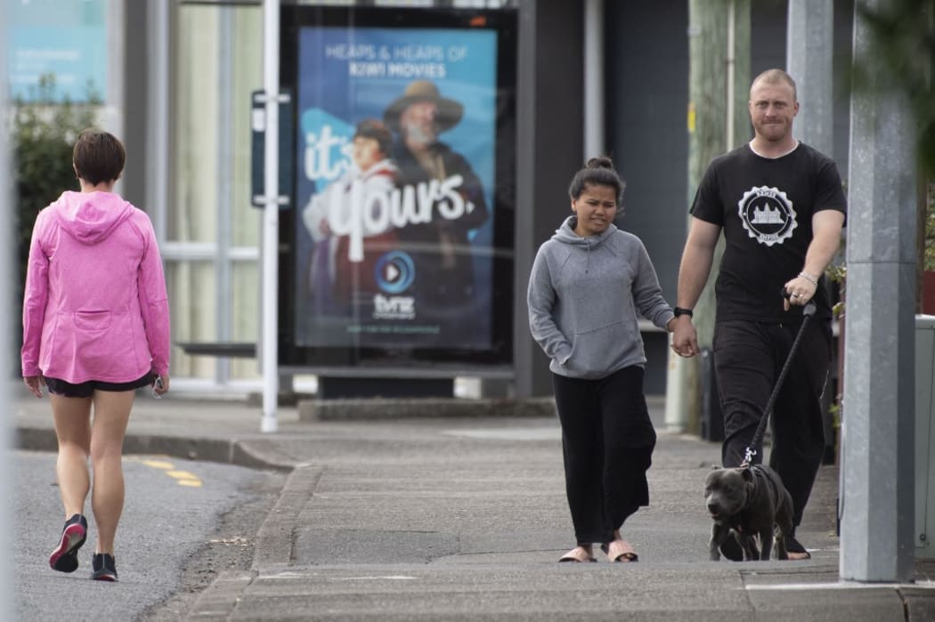 Pedestrians practise social distancing in response to the COVID-19 coronavirus outbreak along a street of Lower Hutt, near Wellington, on April 20, 2020.