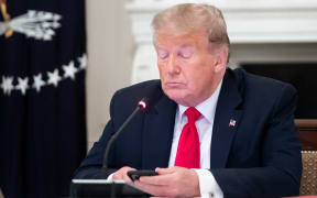 US President Donald Trump uses his cellphone as he holds a roundtable discussion with Governors about the economic reopening of closures due to COVID-19, known as coronavirus, in the State Dining Room of the White House in Washington, DC, June 18, 2020. (Photo by SAUL LOEB / AFP)