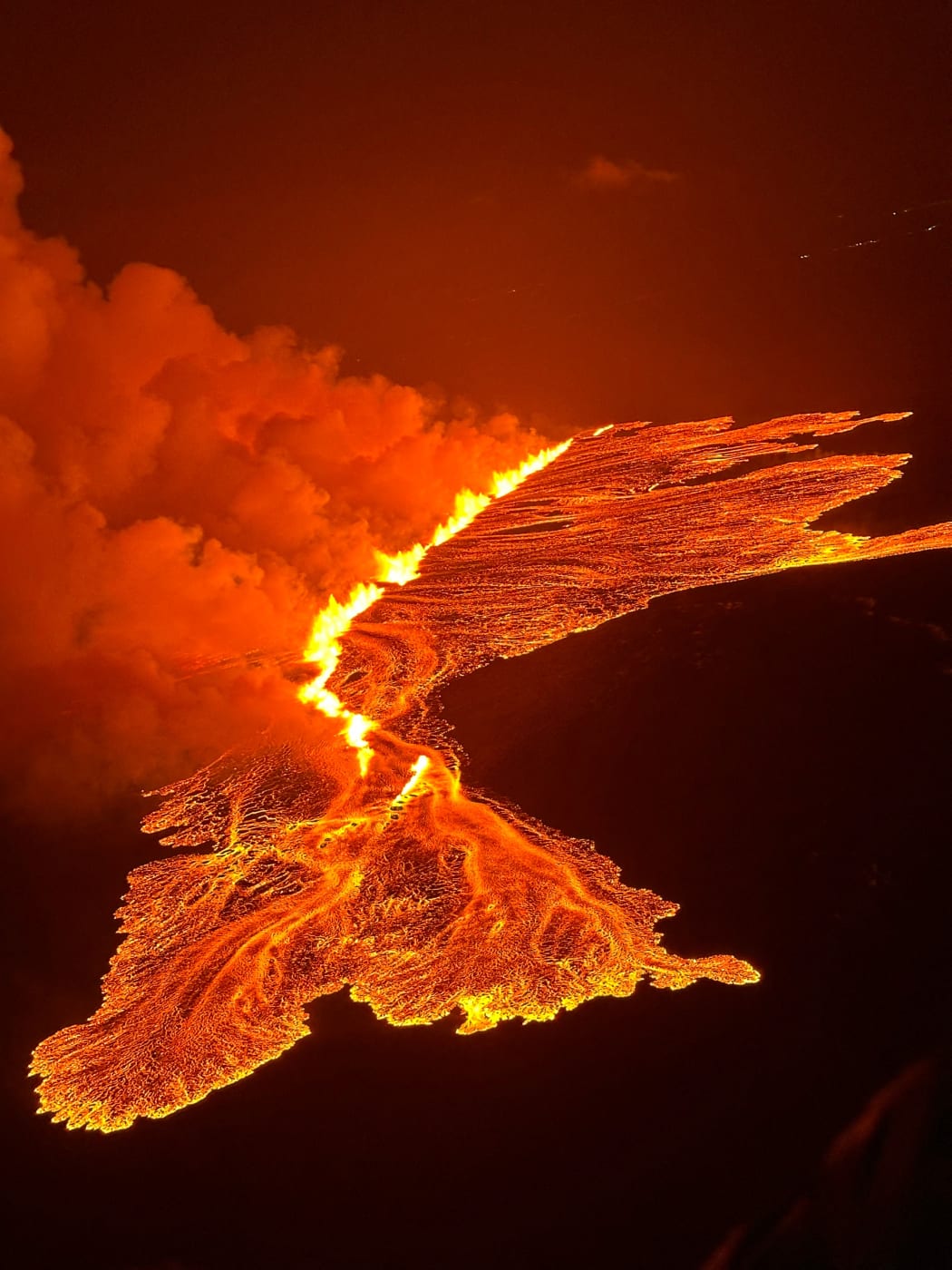 This handout picture released by the Icelandic Coast Guard on March 16, 2024 shows billowing smoke and flowing lava pouring out of a new fissure during a new volcanic eruption on the outskirts of the evacuated town of Grindavik, western Iceland. A volcanic eruption started on the Reykjanes peninsula in southwestern Iceland on Thursday, the third to hit the area since December, authorities said. (Photo by HANDOUT / Icelandic Coast Guard / AFP) / RESTRICTED TO EDITORIAL USE - MANDATORY CREDIT "AFP PHOTO /HANDOUT/ICELANDIC COAST GUARD " - NO MARKETING - NO ADVERTISING CAMPAIGNS - DISTRIBUTED AS A SERVICE TO CLIENTS