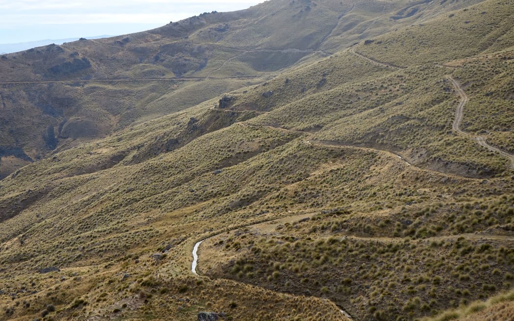 Narrow water channel winds it's way down a brown hillside