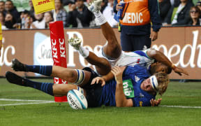 Sam Darry of the Blues scores a try as Simione Kuruvoli of Fijian Drua tackles.
