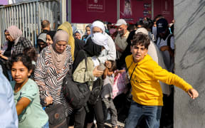 People walk through a gate to enter the Rafah border crossing to Egypt in the southern Gaza Strip on November 1, 2023. Scores of foreign passport holders trapped in Gaza started leaving the war-torn Palestinian territory on November 1 when the Rafah crossing to Egypt was opened up for the first time since the October 7 Hamas attacks on Israel, according to AFP correspondents. (Photo by Mohammed ABED / AFP)