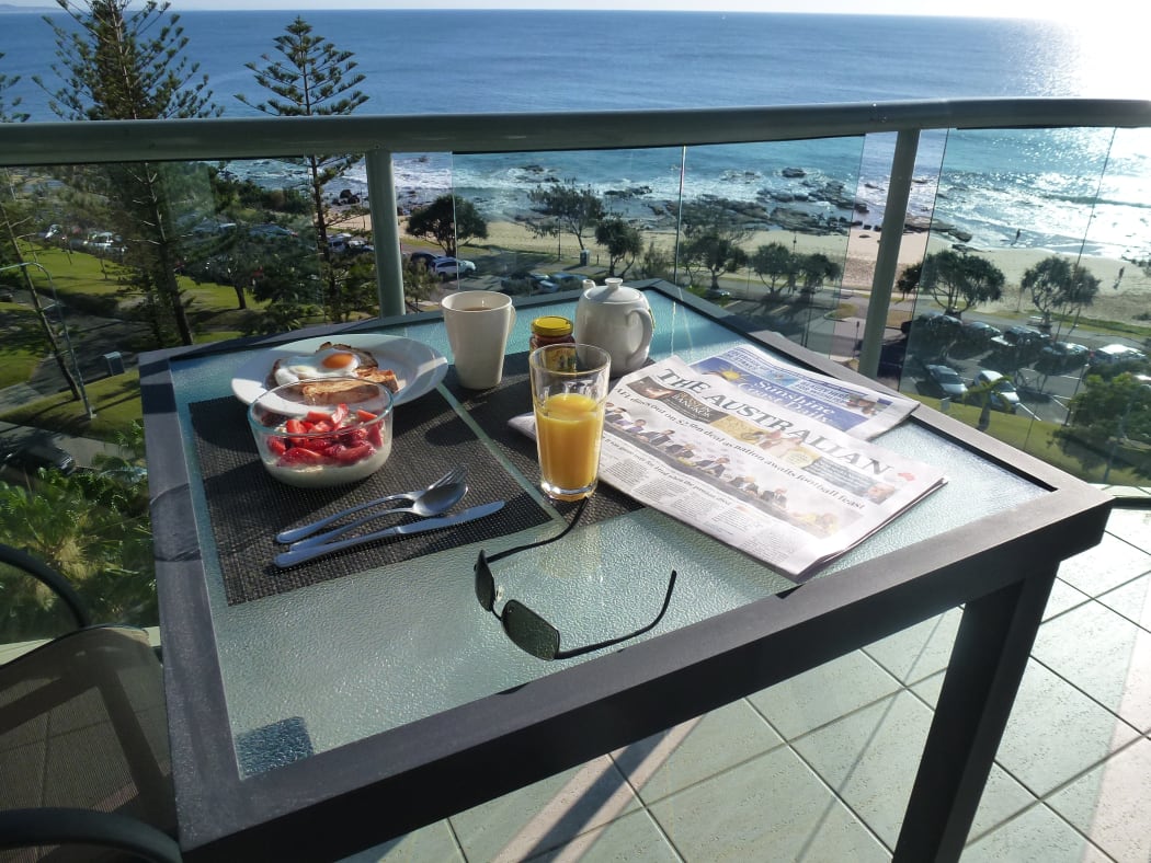 A table with newspaper and breakfast on it