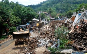An Indonesian search and rescue team joined by volunteers remove debris from an area hit by a landslide in Sumedang on 21 September.