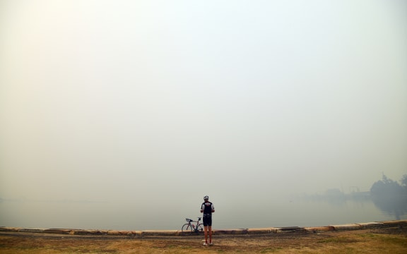 A cyclist takes pictures of smoke from bushfires in Gosford north of Sydney, on Tuesday 10 December.