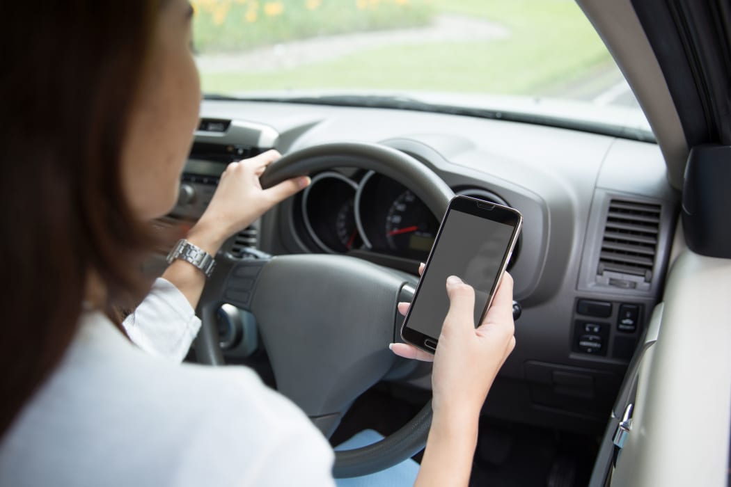 A portrait of a woman  using cellphone inside a car, taken from behind