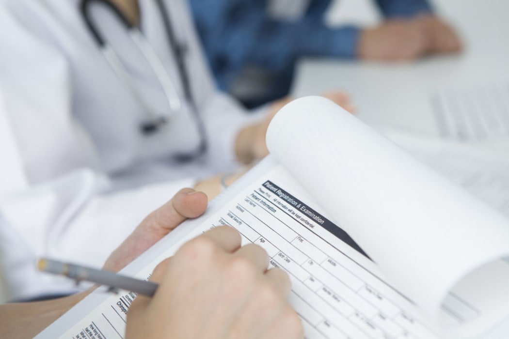 Doctor, nurse of other health worker filling out medical form
