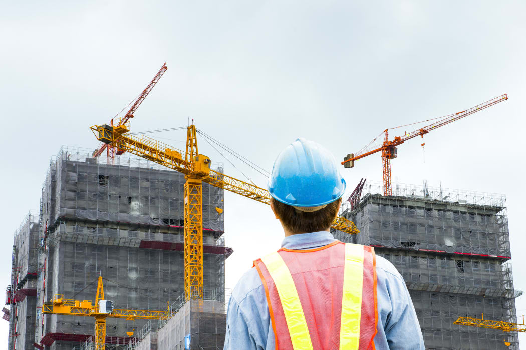 construction worker checking location site with crane on the background