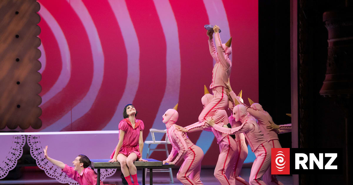 Performers in pink unicorn costumes on a stage with a striped backdrop.